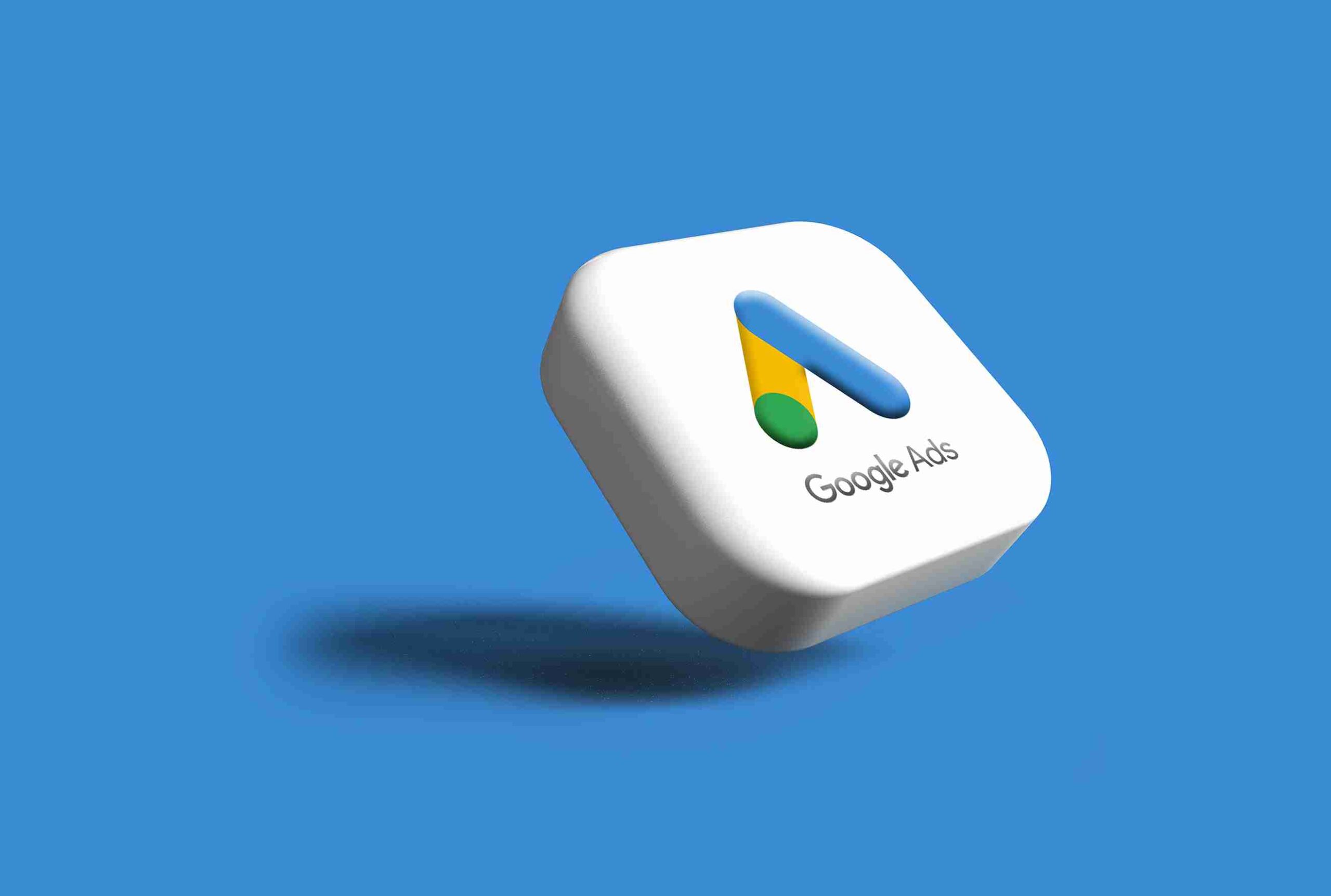The official Google Ads 3D logo, featuring its blue, yellow, and green icon, floating on a solid blue background.